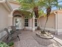 Inviting front entrance with a brick porch, columns, and decorative palm trees with chairs for seating at 2410 Tamarindo Dr, The Villages, FL 32162