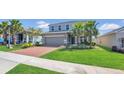 Attractive two-story home with a red brick driveway, green lawn, and palm tree at 3054 Hill Point St, Minneola, FL 34715