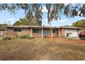 Inviting single story brick home with a covered entry, mature trees, and attached garage at 33311 Green Rd, Leesburg, FL 34788