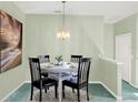 Cozy dining area featuring a glass table with seating for four, complemented by a stylish chandelier and artwork at 4712 St Andrews Arc, Leesburg, FL 34748