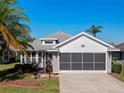 Charming single-story home featuring a screened two-car garage, brick accents and lush landscaping at 4712 St Andrews Arc, Leesburg, FL 34748