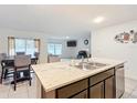 Open-concept kitchen island with stainless steel sink and seating, connecting to the living and dining areas at 4923 Sw 166Th Loop, Ocala, FL 34473
