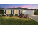 Charming one-story home with white siding, well-manicured lawn and blue shutters at sunset at 5978 Conley Ct, The Villages, FL 32163