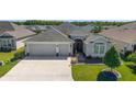 Attractive single-story home with a two-car garage, manicured lawn, and brick walkway leading to the front entrance at 6083 Delphina Loop, The Villages, FL 32163