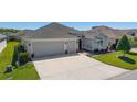 Inviting single-story home showcasing a manicured lawn, brick walkway, and spacious two-car garage at 6083 Delphina Loop, The Villages, FL 32163