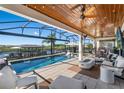 Gorgeous covered outdoor pool and patio with ample seating, a built in bar, and waterfront views at 724 Barefoot Bay Loop, Groveland, FL 34736