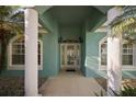 Inviting entryway with decorative glass door, columns, and lush landscaping around the home at 10610 Masters Dr, Clermont, FL 34711