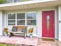 Inviting front porch with a red door, bench, and potted plants at 1108 Cedar St, Leesburg, FL 34748