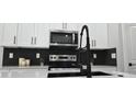 Close up of kitchen featuring stainless steel appliances, white cabinets with black hardware and quartz countertops at 12255 Sw 98Th St, Dunnellon, FL 34432