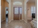 Inviting entryway with leaded glass door, transom window, and tile flooring at 1239 Russell Loop, The Villages, FL 32162