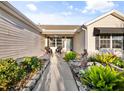 Inviting front entrance featuring a walkway, lush landscaping, and a cozy seating area on the covered porch at 16721 Se 77Th Northridge Ct, The Villages, FL 32162