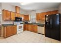 Well-lit kitchen features wooden cabinets, tile flooring, and modern appliances, including a black refrigerator at 1729 Lauren Ln, Lady Lake, FL 32159