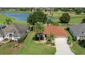 Beautiful aerial view of a well-maintained home with a lush green lawn, mature trees, and serene lake views at 2068 Darlington Dr, The Villages, FL 32162