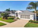 Charming single-story home boasting a gray roof, lush lawn with mature palm trees, and a three-car garage at 27023 Old English Ct, Leesburg, FL 34748