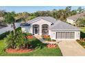 Inviting home exterior with a screened entry, neutral paint, landscaped yard, and a two-car garage at 27023 Old English Ct, Leesburg, FL 34748
