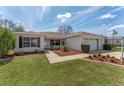 Well-maintained single-story home featuring neat landscaping, an American flag, and a two-car garage at 2712 Benavides Dr, The Villages, FL 32162