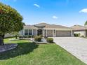 Charming home featuring a well-manicured lawn, mature tree, and brick-paved driveway at 3156 Vandenberg Ct, The Villages, FL 32163