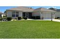 Well-maintained single-story home featuring a lush green lawn and manicured shrubbery at 3183 Hatch Ln, The Villages, FL 32162