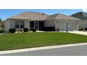 Well-maintained single-story home featuring a lush green lawn and manicured shrubbery at 3183 Hatch Ln, The Villages, FL 32162