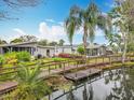 Charming waterfront home featuring a wooden bridge, lush landscaping, and inviting outdoor seating at 3211 Myakka River Rd, Tavares, FL 32778