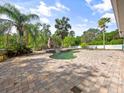 Inviting pool area with a stone patio, lush landscaping, and outdoor fireplace at 3234 Cypress Grove Dr, Eustis, FL 32736
