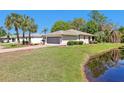 Single-story house overlooking pond features an attached two-car garage, lush lawn, and mature landscaping at 32800 Oak Park Dr, Leesburg, FL 34748