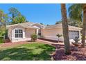 Inviting single-story home with a well maintained lawn, complemented by mature trees and lush tropical foliage at 32800 Oak Park Dr, Leesburg, FL 34748