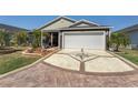 Patterned concrete driveway leading to a two-car garage, complemented by well-maintained landscaping and exterior at 3786 Stephanie Way, The Villages, FL 32163