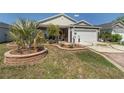 Charming home featuring manicured lawn, decorative landscaping, and a two-car garage with an upgraded driveway at 3786 Stephanie Way, The Villages, FL 32163