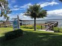 Waterfront property showcasing a private dock, boat house, and lush landscaping under a partly cloudy blue sky at 481 Belle Ayre Dr, Mount Dora, FL 32757