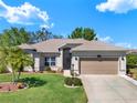 Inviting single-story home featuring a manicured lawn, palm tree, and attached two-car garage at 5645 Huntington St, Leesburg, FL 34748