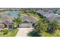 Aerial view showcases the home's prime waterfront location, mature palm trees, and well-maintained lawn at 5835 Hensley Ave, The Villages, FL 32163