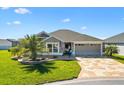 Beautiful home featuring a lovely yard, a patterned driveway, and an attached two-car garage at 6088 Keckonen Dr, The Villages, FL 32163