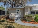 Home entrance featuring well maintained front door and walkway enhanced by surrounding greenery and mulch beds at 103 Tamarisk Way, Leesburg, FL 34748