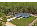 Aerial view of a modern home surrounded by a lush pine forest, showcasing its spacious lot and natural setting at 12444 Sw 76Th Ln, Dunnellon, FL 34432