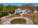 Well-manicured home with mature trees, circular driveway, and solar panels on roof at 12815 Katherine Cir, Clermont, FL 34711