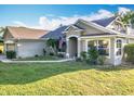 Attractive home featuring an arched entryway, mature landscaping, and an American flag display at 13421 Via Roma Cir, Clermont, FL 34711