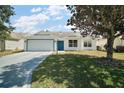 Welcoming single-story home with lush front lawn, attached garage, and bright blue front door at 1419 Segovia Pl, The Villages, FL 32162