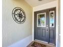 Close-up of the elegant front door with decorative glass and a welcoming 'Hello Summer' doormat at 1430 Hillstream St, The Villages, FL 32163