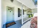 Inviting front porch featuring a light blue door, hanging plants and pretty landscaping at 18319 Dells Cove Rd, Groveland, FL 34736