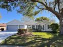 Charming single-story home with well-manicured lawn, mature trees, and a two-car garage at 24614 Stillridge Ct, Leesburg, FL 34748