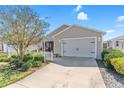 The front exterior showcasing a two-car garage, white picket fence, shrubs, and a concrete driveway at 2602 Young Ln, The Villages, FL 32163