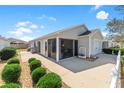 The rear exterior shows a concrete patio, white picket fence, small shrubs, and a screened lanai at 2602 Young Ln, The Villages, FL 32163