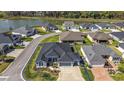 Aerial view of a blue single-Gathering home with a well-manicured lawn, a large lake, and tree-lined streets at 2919 Monument Way, The Villages, FL 32163