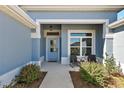 Welcoming front porch featuring a sitting area, a white front door, and beautiful landscaping at 2919 Monument Way, The Villages, FL 32163