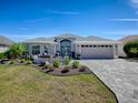 Beautiful single-story home with well-manicured lawn, paver driveway and outdoor fire pit feature at 2922 Rain Lily Loop, The Villages, FL 32163