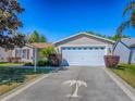 Charming single-story home featuring a two-car garage, pretty landscaping and a uniquely painted palm tree driveway at 337 Olanta Dr, The Villages, FL 32162