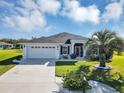 Charming single-story home with a well-manicured lawn, lush landscaping, and a two-car garage at 4419 Clear Brook Ct, Leesburg, FL 34748