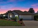 Charming home during twilight featuring a manicured lawn, brick driveway, and a two-car garage at 4571 Abaco Dr, Tavares, FL 32778