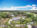 Stunning aerial view of a modern farmhouse home surrounded by lush greenery and mature trees at 464 Long & Winding Rd, Groveland, FL 34736